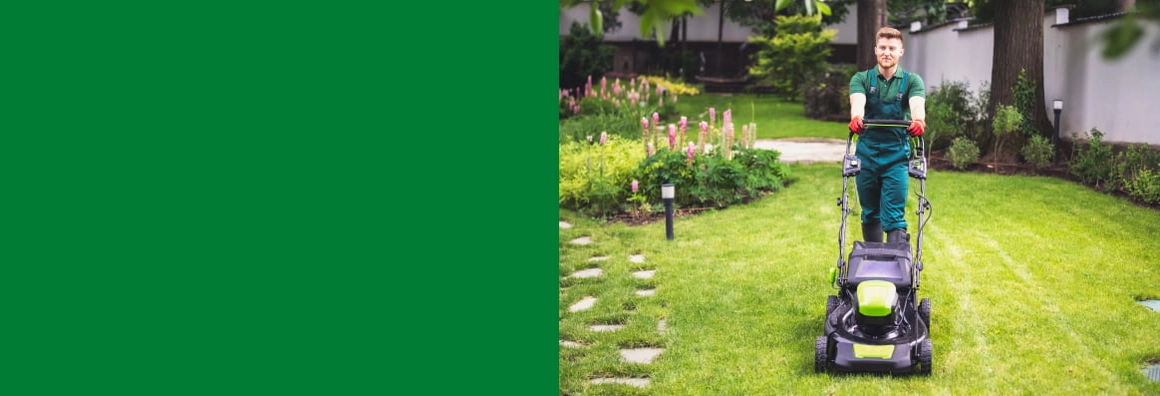 Eine Person mäht mit einem Rasenmäher den Rasen.